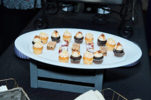 Over a dozen mini cupcakes are placed on an oval white plate.